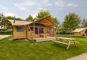 Safari tent called Dune Lodge at Sandberghe in the Netherlands, featuring a wooden terrace and picnic table.