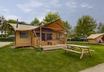 Safari-Zelt Dune Lodge bei Sandberghe in den Niederlanden, mit Holzterrasse und Picknicktisch auf Rasen.