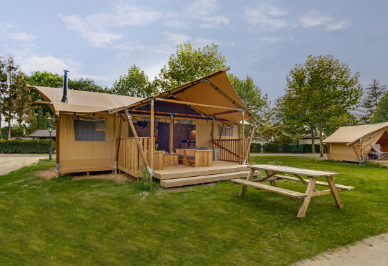 Safari-Zelt Dune Lodge bei Sandberghe in den Niederlanden, mit Holzterrasse und Picknicktisch auf Rasen.
