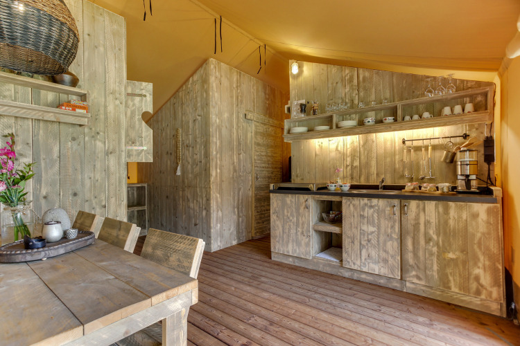 Cocina rústica de madera en una tienda safari en Dune Lodge, Sandberghe, Países Bajos, con comedor.