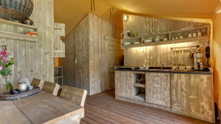 Cocina rústica de madera en una tienda safari en Dune Lodge, Sandberghe, Países Bajos, con comedor.