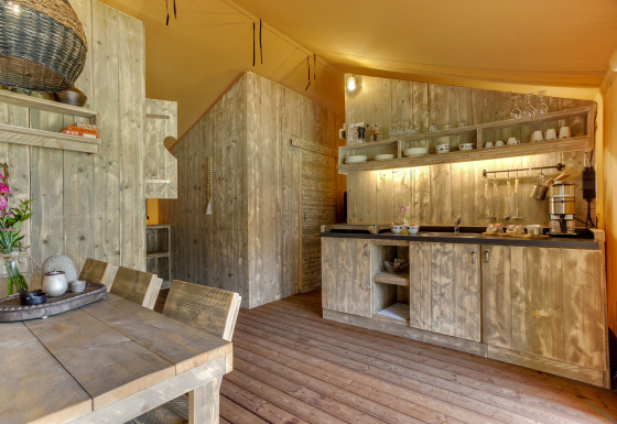 Cocina rústica de madera en una tienda safari en Dune Lodge, Sandberghe, Países Bajos, con comedor.