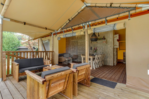 Terrasse en bois avec coin salon et table à manger dans la tente safari Dune Lodge à Sandberghe, Pays-Bas.