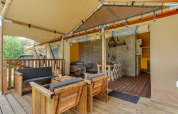 Überdachte Holzterrasse mit Sitzbereich und Esstisch im Safari-Zelt Dune Lodge in Sandberghe, Niederlande.