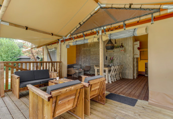 Wooden terrace with seating area and dining table inside the Dune Lodge safari tent at Sandberghe, Netherlands.
