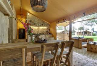 Interieur van Dune Lodge safaritent bij Sandberghe, Nederland, met rustieke eet- en zithoek.