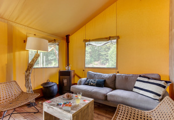 Indretning af Dune Lodge safari telt på Sandberghe i Holland med sofa, stole og rustikke detaljer.