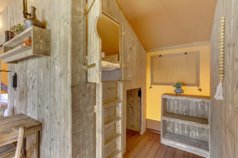 Interieur van safaritent in Dune Lodge bij Sandberghe, Nederland, met houten meubels en bedden.