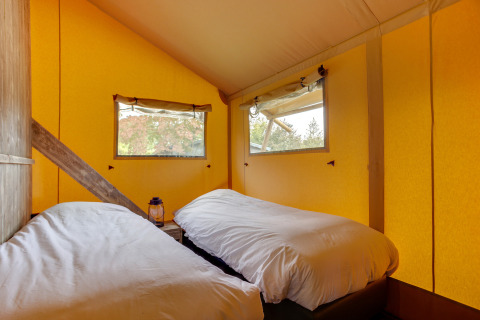 Camas individuales dentro de un acogedor dormitorio de tienda safari en Dune Lodge, Sandberghe, Países Bajos.
