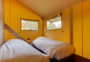 Zwei Einzelbetten in einem gemütlichen Schlafzimmer eines Safarizelts der Dune Lodge, Sandberghe, Niederlande.