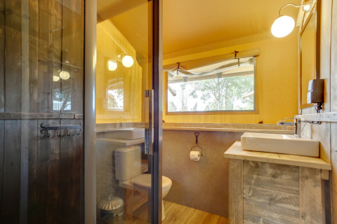 Baño dentro de la tienda safari Dune Lodge en Sandberghe, Países Bajos, con detalles de madera y ventana.