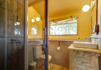 Badezimmer im Safari-Zelt Dune Lodge bei Sandberghe, Niederlande, mit Holzdesign und großen Fenstern.