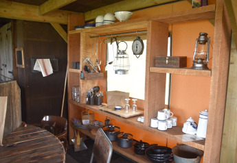 Cucina rustica con scaffali in legno, stoviglie, pentole e lanterna al Beach Lodge Luxury, Duynpark Het Zwanenwater, Paesi Bassi.