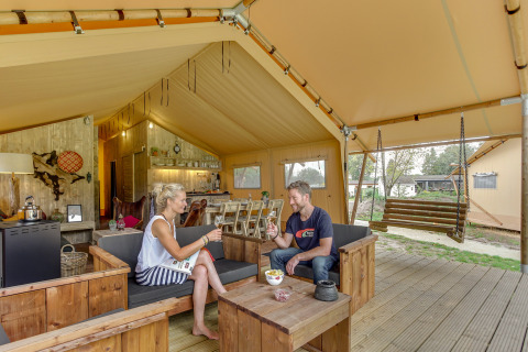 Ein Paar genießt ein Glas Wein im geräumigen Forest Lodge Safari-Zelt bei Sandberghe, Niederlande.