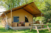 Safari tent Forest Lodge at Sandberghe in the Netherlands, with porch, bench and picnic table outdoors.