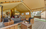 Binnenkant van het Forest Lodge safaritent aan Sandberghe in Nederland met zithoek en houten schommel.