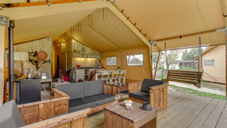 Interior of the Forest Lodge safari tent at Sandberghe in the Netherlands, with lounge and wooden swing bench.