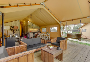 Intérieur de la tente safari Forest Lodge à Sandberghe, Pays-Bas, coin salon et balançoire en bois.