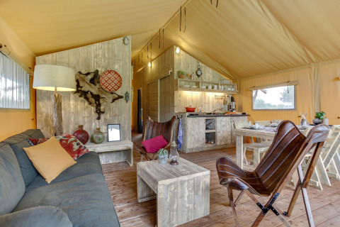 Interior de la tienda safari Forest Lodge en Sandberghe, Países Bajos, con muebles rústicos y ambiente acogedor.