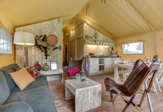 Interior de la tienda safari Forest Lodge en Sandberghe, Países Bajos, con muebles rústicos y ambiente acogedor.