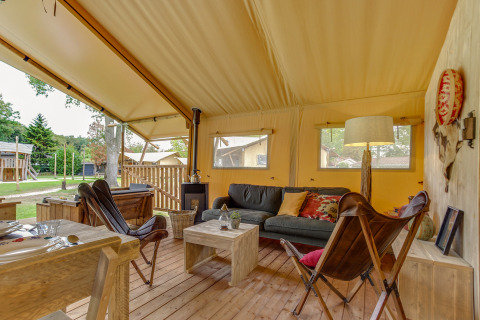 Intérieur d'une tente safari Forest Lodge à Sandberghe, Pays-Bas, avec mobilier confortable et chaleureux.