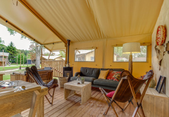 Intérieur d'une tente safari Forest Lodge à Sandberghe, Pays-Bas, avec mobilier confortable et chaleureux.