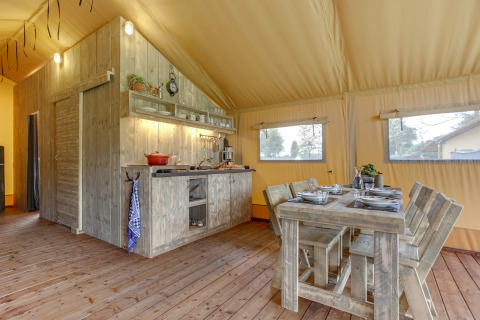Innenraumansicht des Forest Lodge Safari-Zelts in Sandberghe, Niederlande, mit Küche und Esstisch.