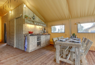 Innenraumansicht des Forest Lodge Safari-Zelts in Sandberghe, Niederlande, mit Küche und Esstisch.