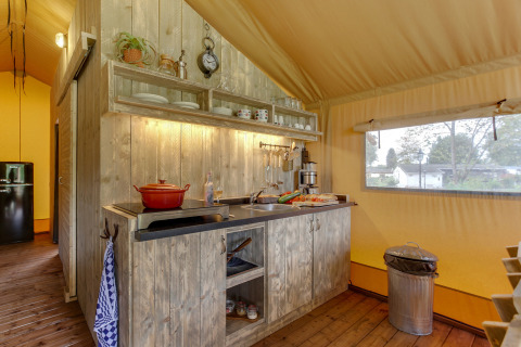 Cucina all'interno di una tenda safari alla Forest Lodge, Sandberghe, Paesi Bassi, con armadi rustici.