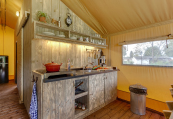 Køkkenområdet i et safaritelt på Forest Lodge, Sandberghe, Holland, med træskabe og vindue.
