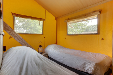 Zwei Einzelbetten im gemütlichen Schlafbereich eines Safarizelts im Forest Lodge in Sandberghe, Niederlande.