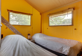 Twee aparte bedden in een warme slaaphoek van een safaritent bij Forest Lodge, Sandberghe, Nederland.
