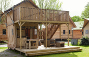 Tienda safari Forest Lodge Junior en Sandberghe, Países Bajos, con terraza y balcón de madera al aire libre.