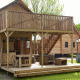 Tienda safari Forest Lodge Junior en Sandberghe, Países Bajos, con terraza y balcón de madera al aire libre.