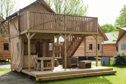 Safari tent Forest Lodge Junior bij Sandberghe in Nederland met houten terras, balkon en buitenzitje.