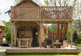 Safari-Zelt Forest Lodge Junior bei Sandberghe, Niederlande, mit Holzterrasse und gemütlichen Sitzgelegenheiten.