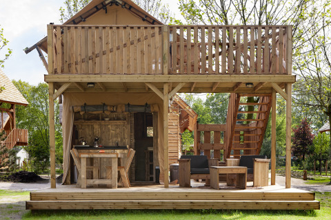Safari-Zelt Forest Lodge Junior bei Sandberghe, Niederlande, mit Holzterrasse und gemütlichen Sitzgelegenheiten.