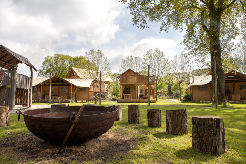 Tenda safari Forest Lodge Junior a Sandberghe, Paesi Bassi, con focolare e sedute in tronchi d’albero.