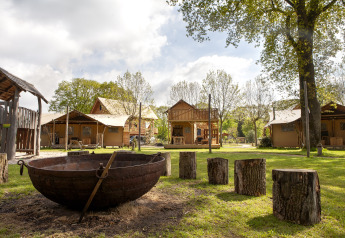 Safari tent Forest Lodge Junior bij Sandberghe in Nederland, met vuurkorf en boomstammen als zitjes.