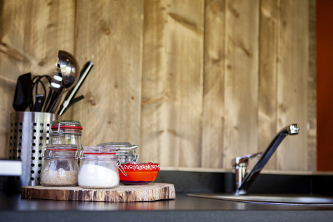 Piano cucina con barattoli di vetro, ciotole rosse, utensili e rubinetto al Forest Lodge Junior, Sandberghe.