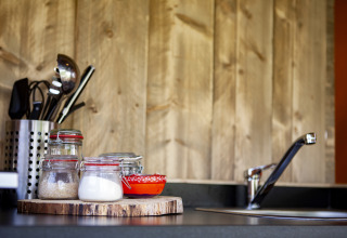 Piano cucina con barattoli di vetro, ciotole rosse, utensili e rubinetto al Forest Lodge Junior, Sandberghe.