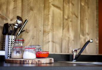 Piano cucina con barattoli di vetro, ciotole rosse, utensili e rubinetto al Forest Lodge Junior, Sandberghe.