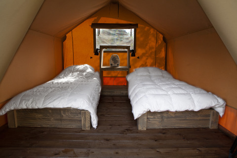 Interno di tenda safari con due letti singoli e biancheria bianca al Forest Lodge Junior a Sandberghe.