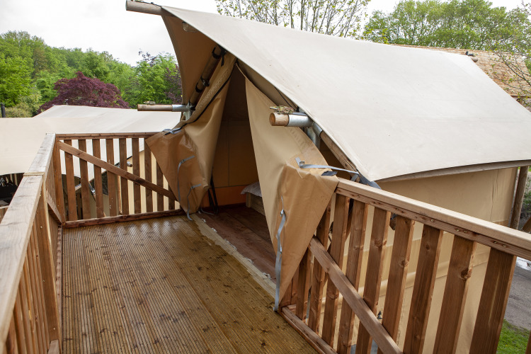 Terraza de madera frente a la entrada de una tienda safari abierta en Forest Lodge Junior, Sandberghe.