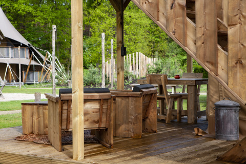 Houten terras met rustieke stoelen bij safaritent Forest Lodge Junior, Sandberghe, Nederland.