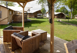 Vista da una terrazza coperta con sedie in legno sulle tende safari Forest Lodge Junior a Sandberghe, Paesi Bassi.