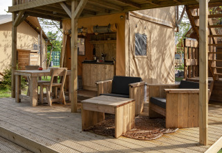 Zona exterior con muebles de madera y cocina en una tienda safari, Forest Lodge Junior en Sandberghe, Países Bajos.