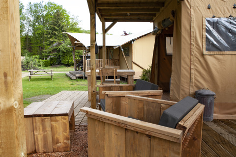 Zona exterior con muebles de madera en la tienda safarí Forest Lodge Junior de Sandberghe, Países Bajos.