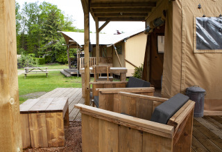 Zona exterior con muebles de madera en la tienda safarí Forest Lodge Junior de Sandberghe, Países Bajos.