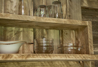 Estantes de madera con vasos y cuencos en una tienda safari en Forest Lodge Junior de Sandberghe, Países Bajos.